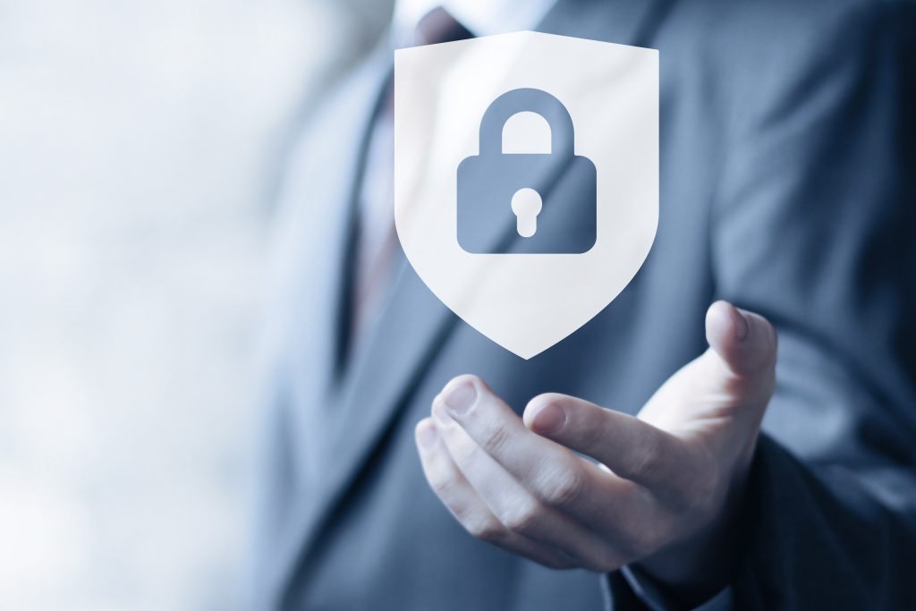 person in business suit holding out hand with an image of a shield with a padlock inside it hovering above