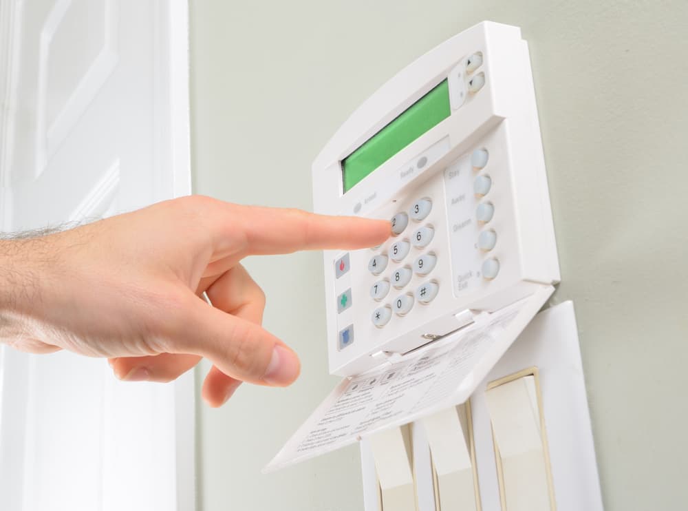 Person pointing towards buttons on open home security system panel